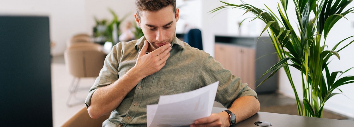 Portret van een gefocuste mannelijke klant die het contract voor de aankoop van onroerend goed leest.