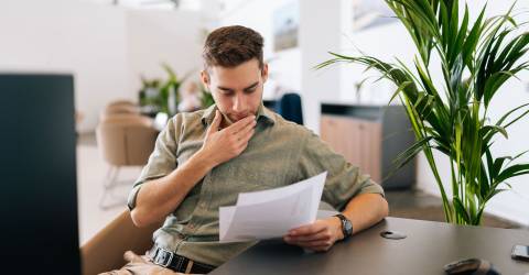 Portret van een gefocuste mannelijke klant die het contract voor de aankoop van onroerend goed leest.